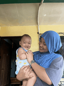 a woman holding a baby wearing a watch that says rolex
