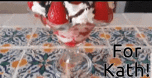 a glass filled with strawberries and whipped cream on a table