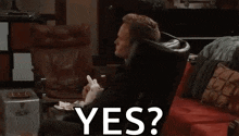 a man is sitting on a couch holding a small white rabbit and asking yes .
