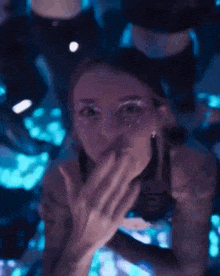 a woman is covering her mouth with her hand in a dark room .