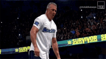 a man in a white shirt is jumping in the air with his arms outstretched in front of a sign that says survivor series