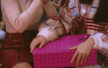 a woman in a striped sweater is holding a pink gift