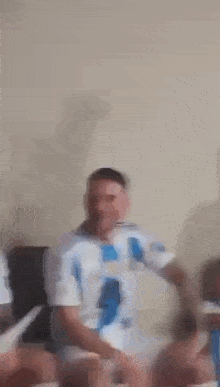 a man in a blue and white striped shirt is giving the middle finger .