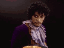 a man in a purple jacket holding a plate of pancakes