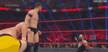 two men are wrestling in a wrestling ring with a crowd in the background .