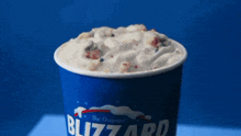 a cup of blizzard ice cream is on a blue table