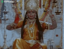 a woman in a costume is sitting on a throne in a temple holding a candle .