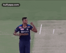 a cricket player in a blue jersey is standing on a field .