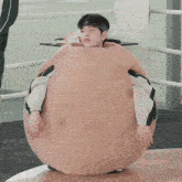 a man is sitting inside of a large brown sphere with korean writing on it