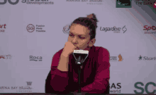a woman sitting at a table with a microphone in front of a sign that says sg
