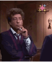 a man in a suit and tie is smoking a cigarette and looking at himself in the mirror .