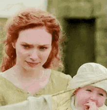 a woman is holding a baby in her arms and the baby is making a funny face .