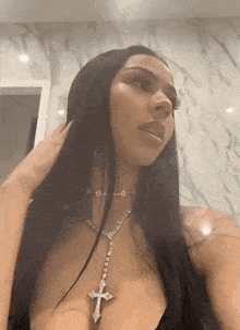 a woman is wearing a necklace with a cross on it