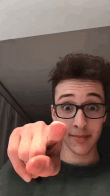 the man is wearing glasses and pointing at the camera .