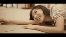 a woman in a plaid shirt is smiling and laying on the floor