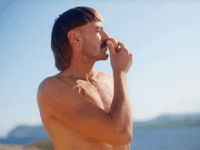 a shirtless man with a mullet and mustache holds his nose