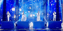 a group of people are standing on a stage with microphones in front of a blue background .