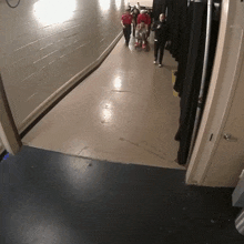 a group of people walking down a hallway with a man in a red shirt