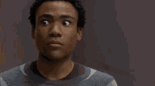a man in a striped sweater is making a funny face while looking at the camera .