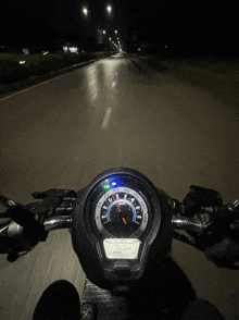 a motorcycle is driving down a road at night and the speedometer shows that it is going at a very high speed