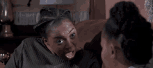two women are sitting on a couch talking to each other and one of them has a surprised look on her face