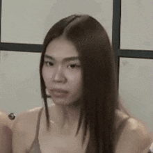 a woman with long brown hair is making a funny face while wearing a bra .