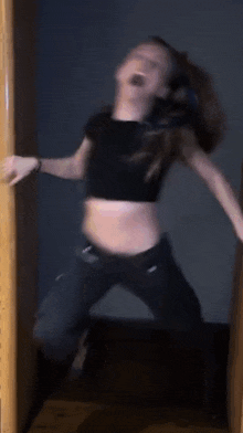 a woman in a crop top is jumping in the air with her mouth open .