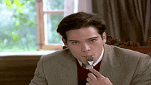 a man in a suit is eating a piece of meat with a fork .