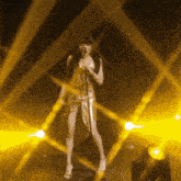 a woman singing into a microphone in front of yellow lights