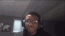 a man wearing headphones and glasses is looking at the camera .
