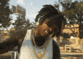 a man wearing sunglasses and a gold chain has a tattoo on his face