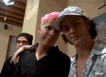 a man with pink hair is posing for a picture with another man