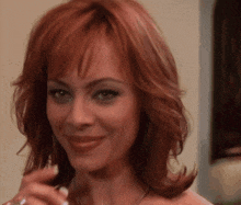 a close up of a woman 's face with red hair smiling
