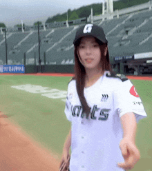 a woman wearing a giants jersey is standing on a baseball field