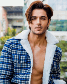 a shirtless man wearing a plaid jacket with a white fur collar