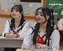 two girls in school uniforms are sitting in a classroom with a free fire logo in the background