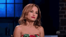 a woman in a strapless dress is sitting in front of a window on a television show .