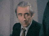 a man in a suit and tie looks to the side