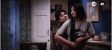 a man and a woman are hugging in a room with the word alt on the bottom