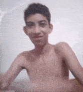 a shirtless boy is smiling and looking at the camera .
