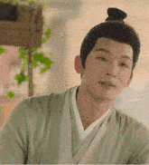 a young man with a bun on his head looks at the camera