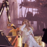 a woman in a white dress is sitting on a stage holding a bottle of champagne