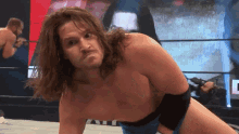 a wrestler without a shirt is kneeling on the ground