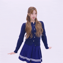 a girl wearing a blue cardigan and a blue skirt stands with her arms outstretched