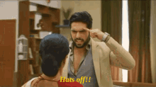a man with a beard is pointing his finger at his forehead while a woman says " hats off "