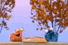 elmo and cookie monster are standing next to each other on a balcony looking at a book .