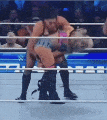 a man and a woman are wrestling in a wrestling ring with a crowd watching
