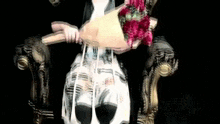 a girl is sitting in a chair holding a bouquet of flowers .