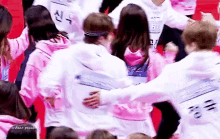 a group of people are hugging each other in a crowd while wearing pink sweatshirts .
