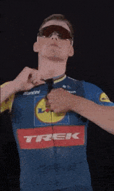 a man wearing sunglasses and a blue shirt that says trek on it